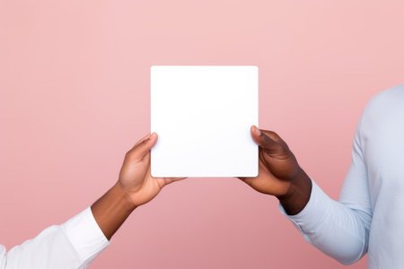 mans holding a blank placard sign poster paper in his hands on pastel pink backgroundの素材