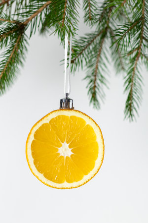 Creative christmas decoration: orange slice ornament hung on pine branch with white background.の写真素材