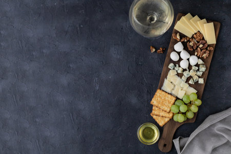 Gourmet cheese and wine pairing with crackers, grapes, and nuts on rustic board.