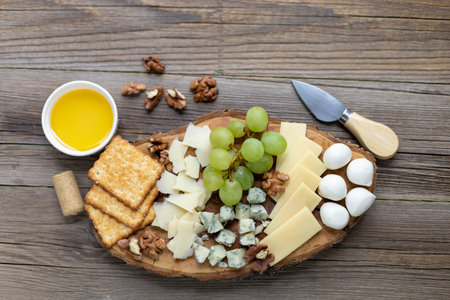 Cheese platter with grapes, crackers, and nuts on rustic wooden table.の写真素材