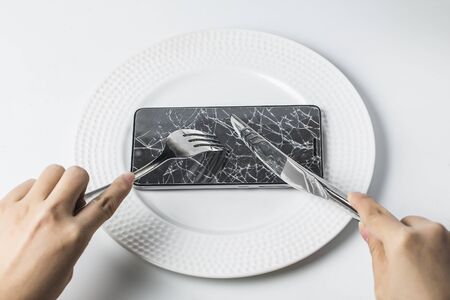 concept image-mobile phone as meal to having by knife & forkのeditorial素材