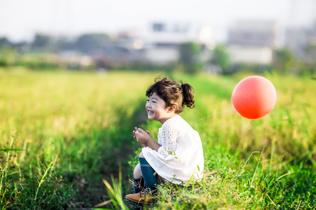 Little girl playing with balloons on wheat fieldのeditorial素材