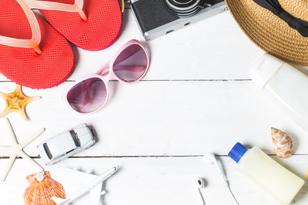 Beach accessories. Bag, towel, sunglasses and flip-flops on wooden background. Top view with copy spaceの写真素材