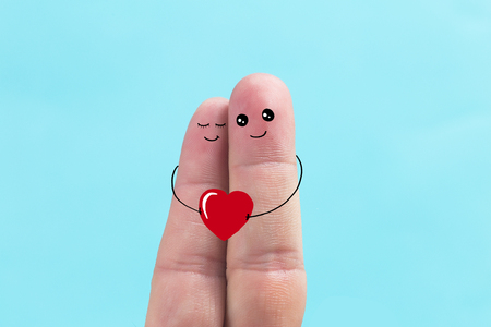 Happy couple in love with painted smiley holding red heartの写真素材