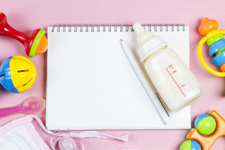 Baby accessories. Wooden toys, pacifier and bottle on Pink background top view copyspaceの写真素材