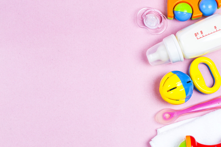 Baby accessories. Wooden toys, pacifier and bottle on Pink background top view copyspaceの写真素材