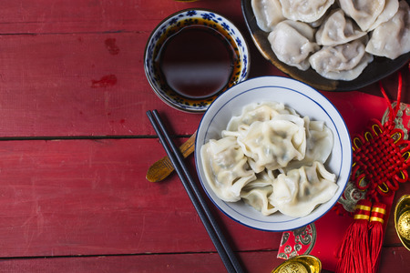 a bowl of chinese dumplings with ingot and red knot as backgroundの写真素材