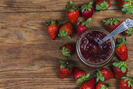 Jar of strawberry jam on  wooden background from top viewの写真素材