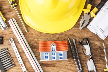Construction tools and house model on wooden table