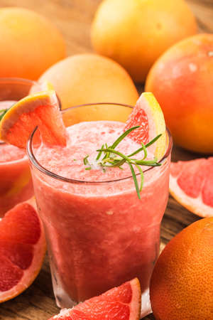 Grapefruit juice with rosemary and ice in a glass on the table. Refreshing summer cocktailの写真素材