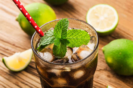 Fresh made Cuba Libre with brown rum, cola, mint and lemon on wooden backgroundの写真素材