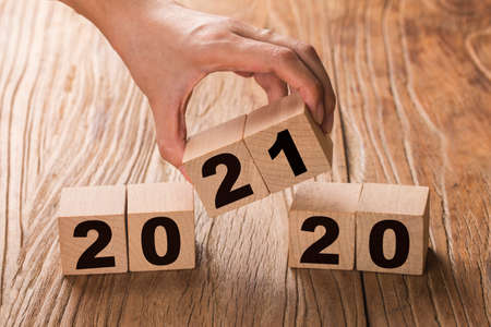 Hand flips a block changing 2020 to 2021. New year beginning. Holidays and Christmas.の写真素材