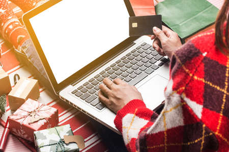Christmas online shopping. Female buyer with laptop, prepare to xmas eve, sitting among gifts boxes and packages. Winter holidays salesの写真素材