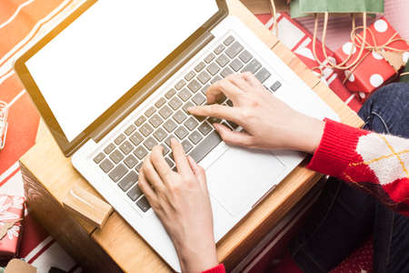 Christmas online shopping. Female buyer with laptop, prepare to xmas eve, sitting among gifts boxes...