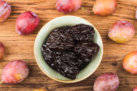 Fresh prune and dried prune on wooden board backgroundの写真素材