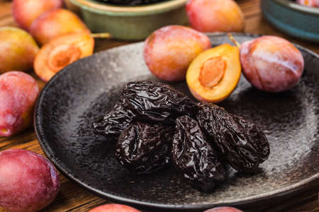 Fresh prune and dried prune on wooden board backgroundの写真素材
