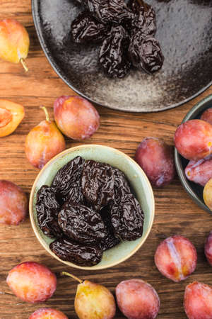 Fresh prune and dried prune on wooden board backgroundの写真素材