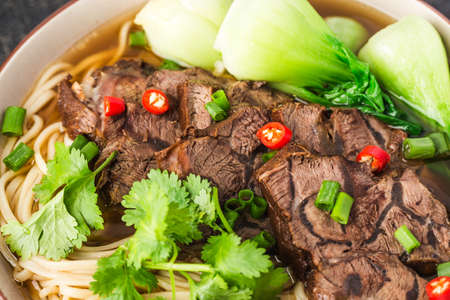 Spicy red soup beef noodle in a bowl on wooden table