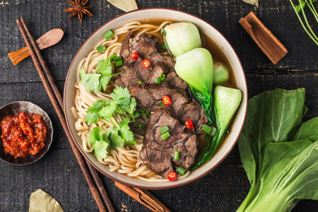 Spicy red soup beef noodle in a bowl on wooden tableの写真素材