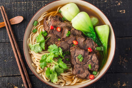 Spicy red soup beef noodle in a bowl on wooden tableの写真素材