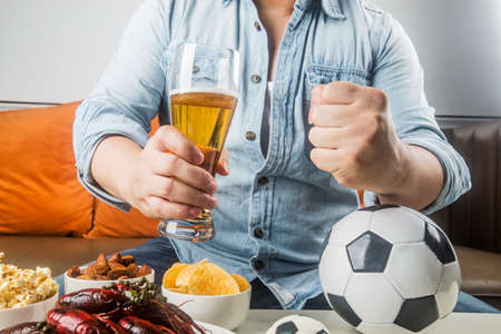 Eating snacks and beer and watching football liveの写真素材
