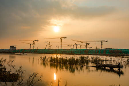 Construction site with cranes and building materials at sunset in Thailand.の写真素材