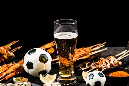 A variety of barbecue dishes and beer are placed on the black wooden background. Watch football and eat barbecueの写真素材
