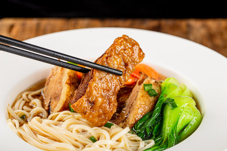 Spicy soup red beef noodle in a bowl on wooden tableの写真素材