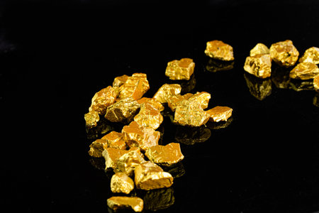 Gold nuggets on a black background with reflection. Studio shot.