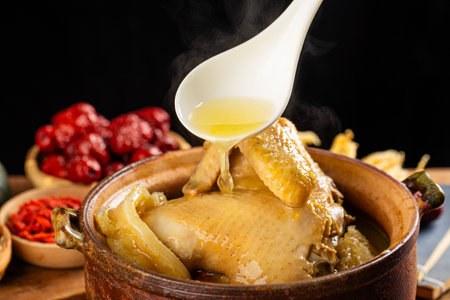 Chicken stewed in a clay pot with a spoon on a black backgroundの写真素材