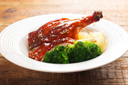 Roast duck with broccoli and lemon on a white plate, closeupの写真素材