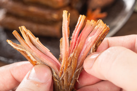 Close up of a man's hands holding a piece of dried meat