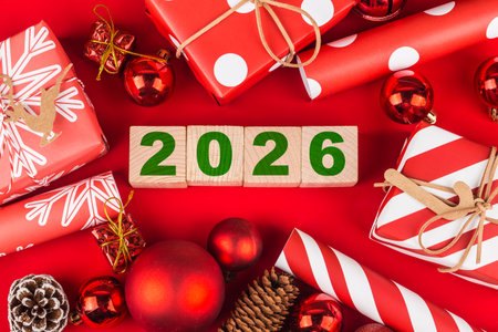 Wooden blocks with the date of 2026 on a red background with Christmas decorations and gifts