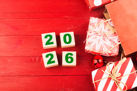 Wooden cubes with numbers 2026 and Christmas decorations on a red wooden background