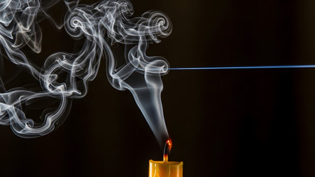 White smoke from a yellow candle creates abstract swirling patterns near a thin blue light beam...の写真素材