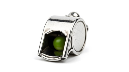Detailed shot of a silver metal whistle with a green pea inside, set against a plain white backdrop.