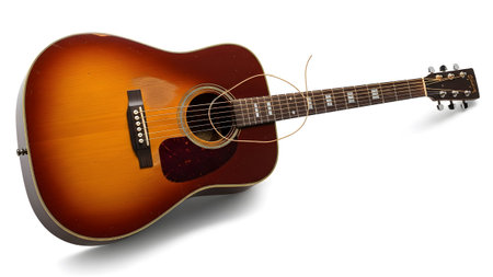 Hobby showing sunburst acoustic guitar with tortoiseshell pickguard and coiled string on white...