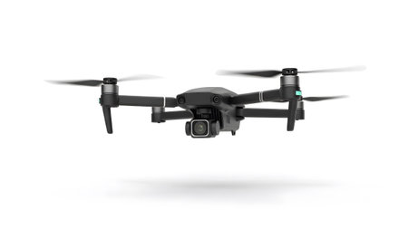 A dark grey drone with a camera and spinning propellers is shown isolated on white....