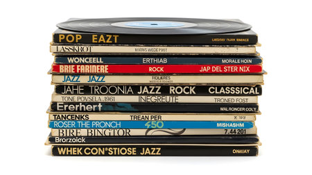 A tall stack of vintage vinyl record albums with colorful spines and a single black record on
