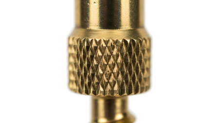Detailed macro view of a shiny brass screw component featuring a precise diamond knurled texture...