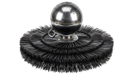 A black wire brush with layered circular bristles and a metallic sphere suspended at its center...