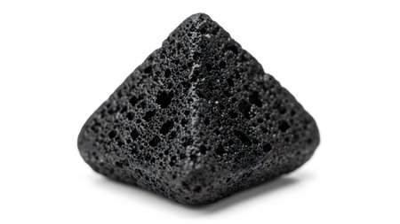 A small, pyramid-shaped black volcanic pumice stone with a distinctly porous and rough texture,...