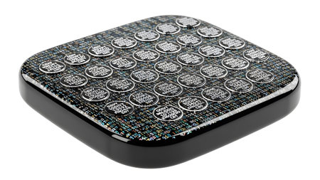 With showing square black device with a textured surface displaying rows of circular buttons...