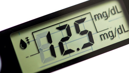 (5708) showing close up of a digital glucose meter screen displaying a sugar reading of 82.5...