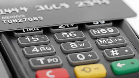 Macro view of a credit card positioned over a gray keypad on a payment terminal, showing...