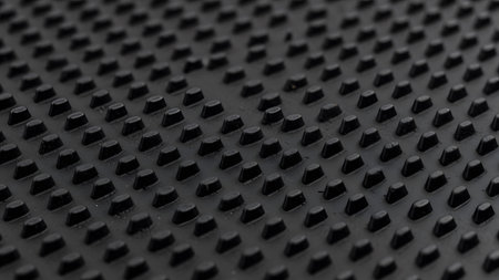 Pattern showing close-up of black textured surface with raised circular studs in a grid pattern....の写真素材