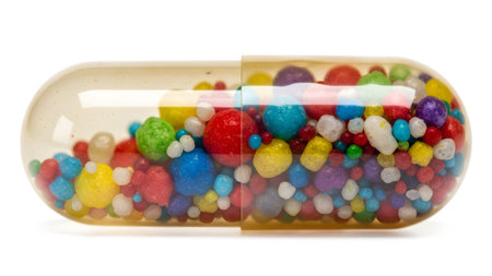 A transparent capsule filled with numerous small, brightly colored round candy balls and...