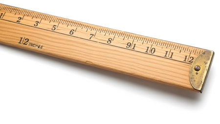 A close-up view of a wooden folding ruler showing inch markings and a brass end cap on a white...