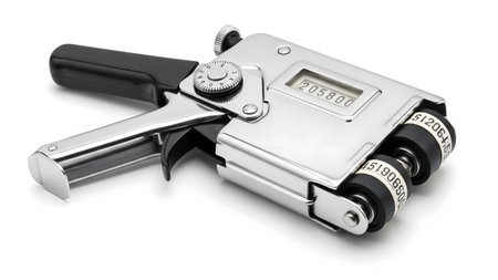 A silver and black price labeling gun with a digital display and two wheels showing sequential...
