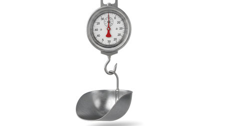 A vintage spring scale with a metal scoop hangs from a hook, displaying measurements on a...